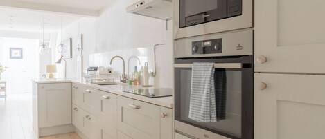 Una cocina moderna con horno empotrado, microondas y pileta de acero inoxidable.