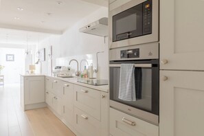 Una cocina moderna con horno empotrado, microondas y pileta de acero inoxidable.