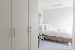 A bedroom with a bed, a bedside table, and a wardrobe.