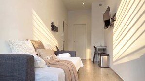 Habitación de hotel con cama, una silla, una mesita, un televisor y una puerta.