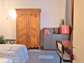 A compact room with a bed, a wooden wardrobe, a kitchenette with a pink fridge, and a dining area. - Cinisca, stunning design apartment (Bologna)