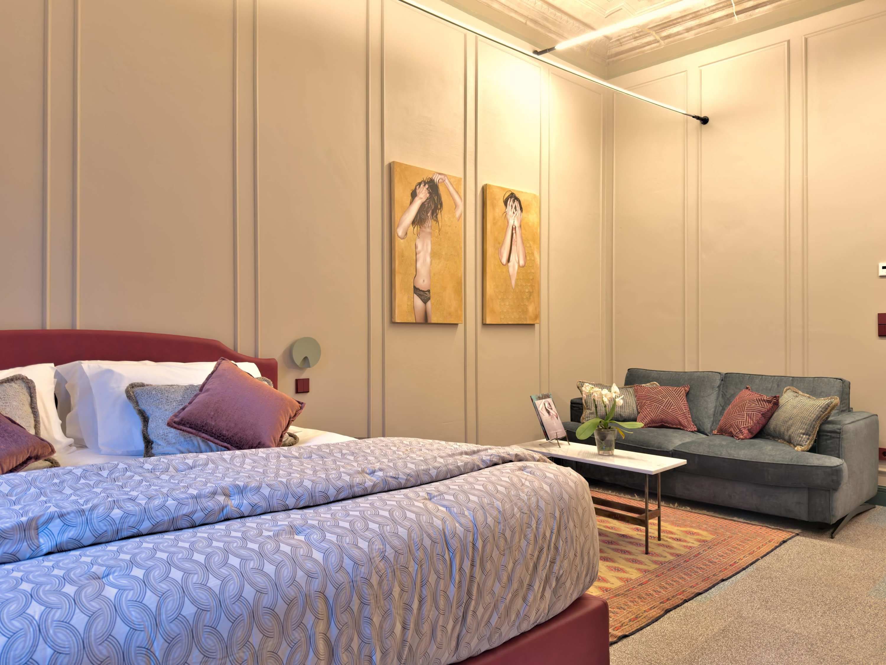 Une chambre à coucher avec un lit, un canapé et deux tableaux accrochés au mur.