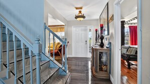 A hallway with a blue staircase, a white door, and a console table with decorative items.