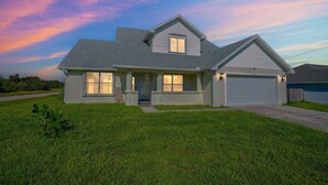 A two-story house with a garage, a front porch, and a well-maintained lawn.