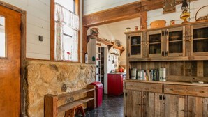 A rustic kitchen with wooden cabinets, a stone bench, and a red countertop. - Hideaway Cabin 3 Bedroom Cabin (Uvalde)