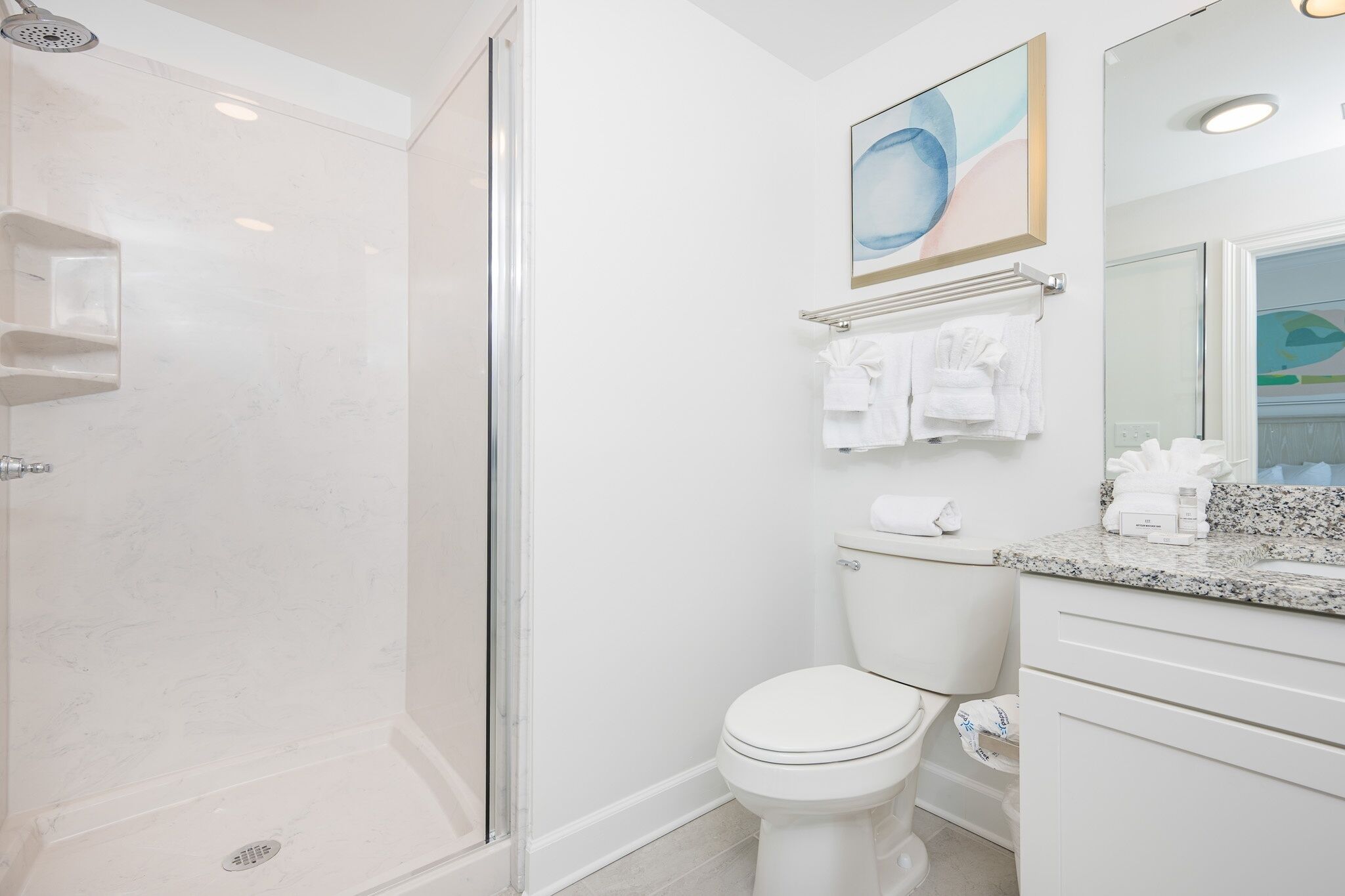 A modern bathroom with a glass-enclosed shower, a toilet, and a vanity with a mirror.