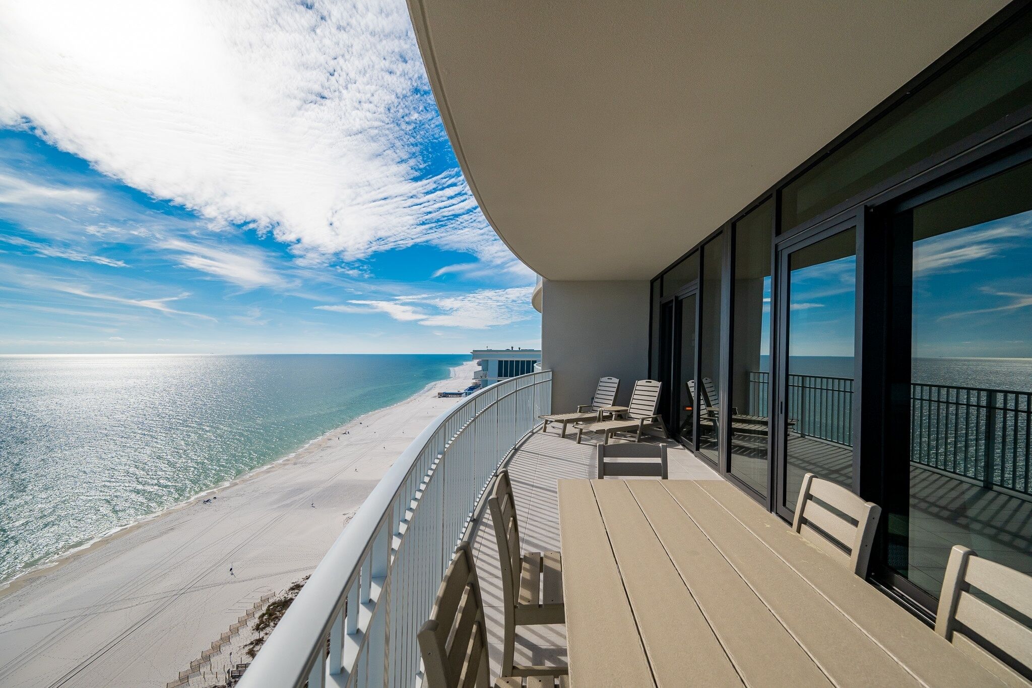 A balcony with a view of the beach and ocean.