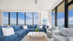 A modern living room with a large blue sectional sofa, a grey armchair, and a wooden coffee table.