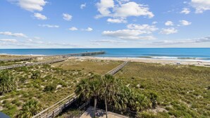 A beach with a wooden boardwalk, palm trees, and a clear blue sky.