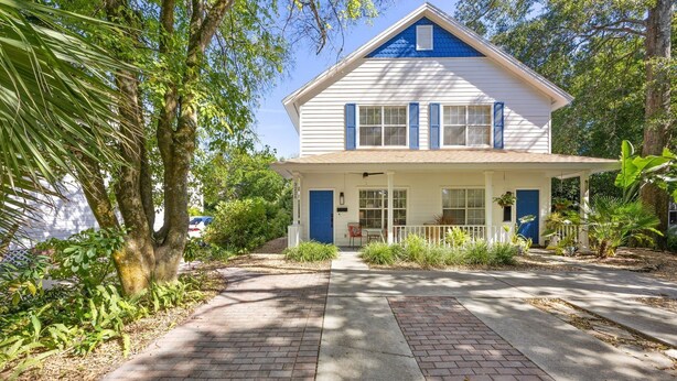 A two-story house with a front porch, surrounded by lush greenery and trees. - 322 S. 5th Street Unit A 3 Bedroom Townhouse (Fernandina Beach)