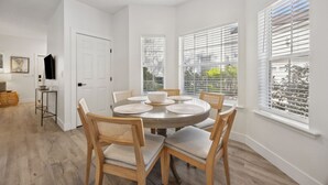 A dining area with a round table, six chairs, and a white door in the background. - 322 S. 5th Street Unit A 3 Bedroom Townhouse (Fernandina Beach)