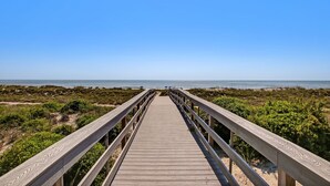A wooden boardwalk leading to a beach with a clear sky.