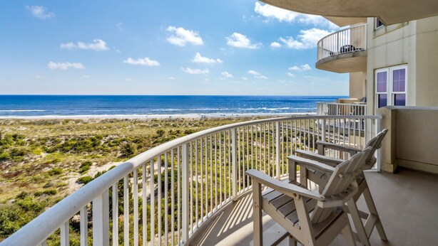 A balcony with a view of the beach and ocean.