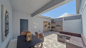 Un patio al aire libre con una mesa, sillas, una puerta y un muro con detalles decorativos.