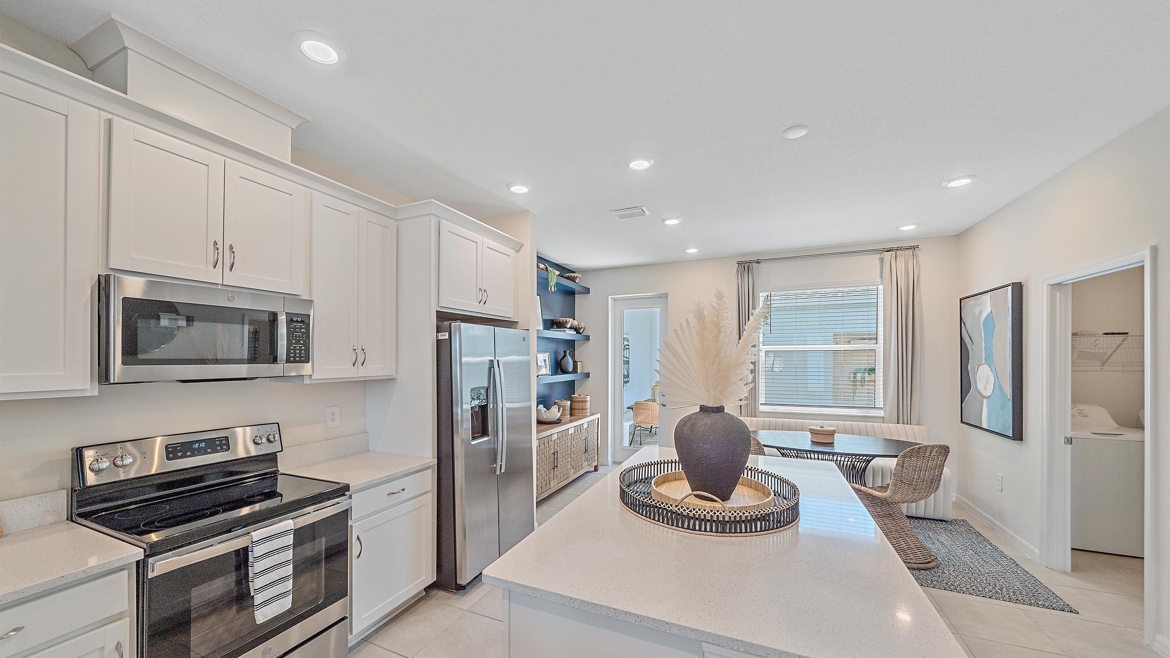 A modern kitchen with white cabinetry, stainless steel appliances, and a central island with a decorative bowl.