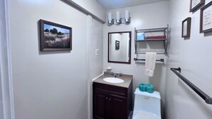 Une salle de bain avec un lavabo, un miroir, des toilettes et des tableaux encadrés accrochés au mur.