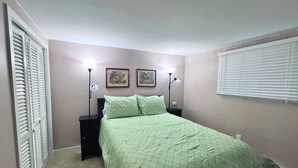 Une chambre à coucher avec un lit, deux lampes de chevet, une table de chevet et une fenêtre avec des stores.