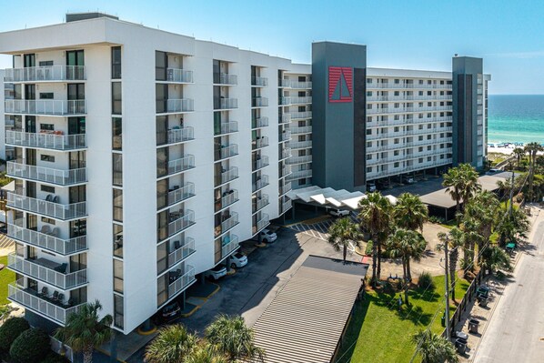 Un hotel de varios pisos con balcones, un estacionamiento y vista a la playa.