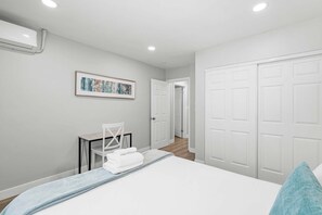 Une chambre à coucher comprenant un lit, un bureau, une chaise et une porte donnant sur une autre pièce.