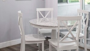 A dining area with a round table and white chairs, a ceiling light, and a window with curtains. - Chic Modern Stay w Patio Near LA Best Sights6 (Altadena)