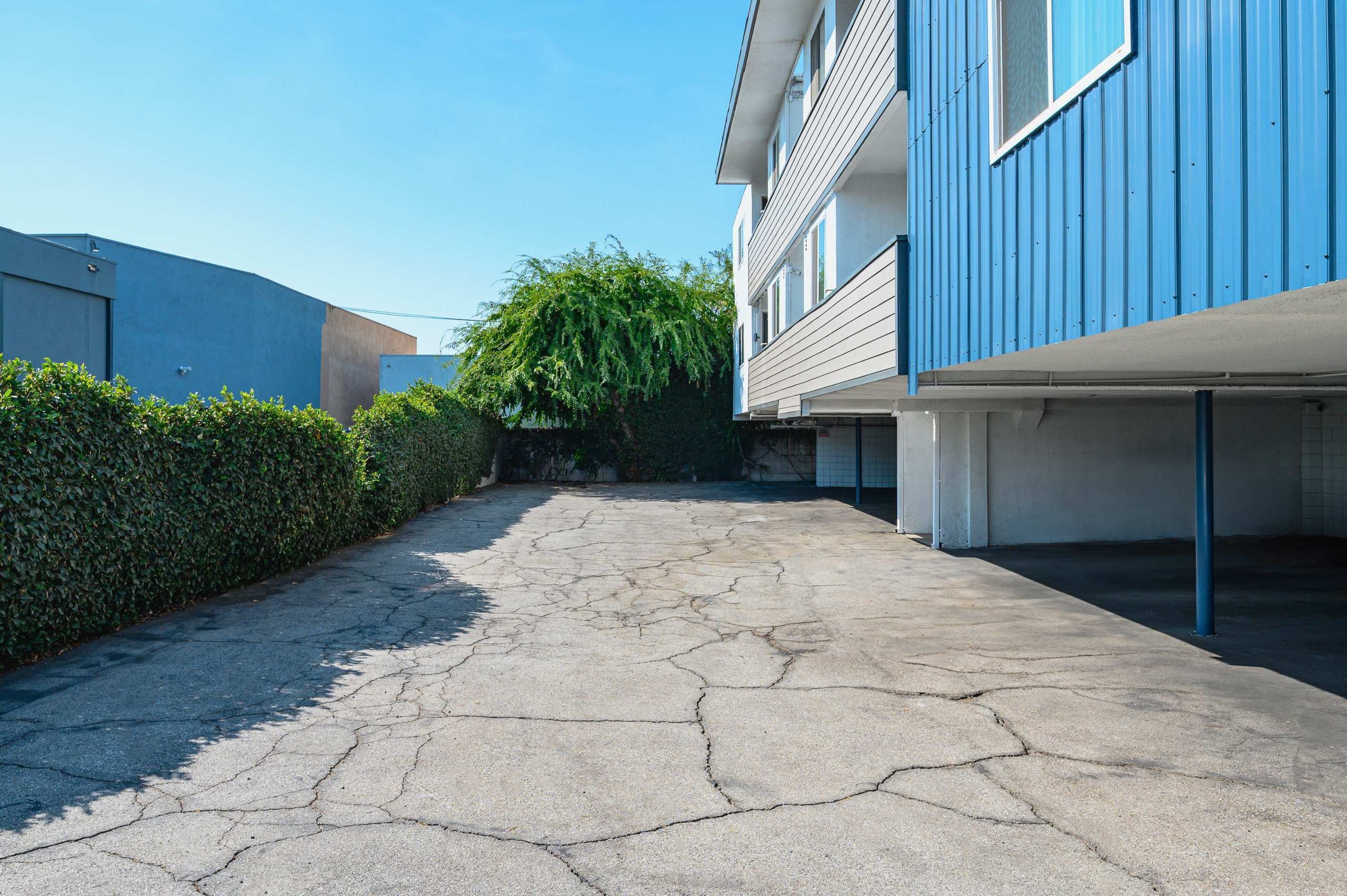 A paved driveway leading to a building with a blue exterior and a covered garage.
