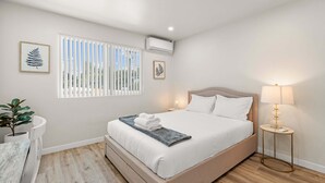 A neatly arranged bedroom with a bed, bedside table, lamp, and potted plant. - Stylish Home w Free Parking Near LA Hotspots 8 (Altadena)
