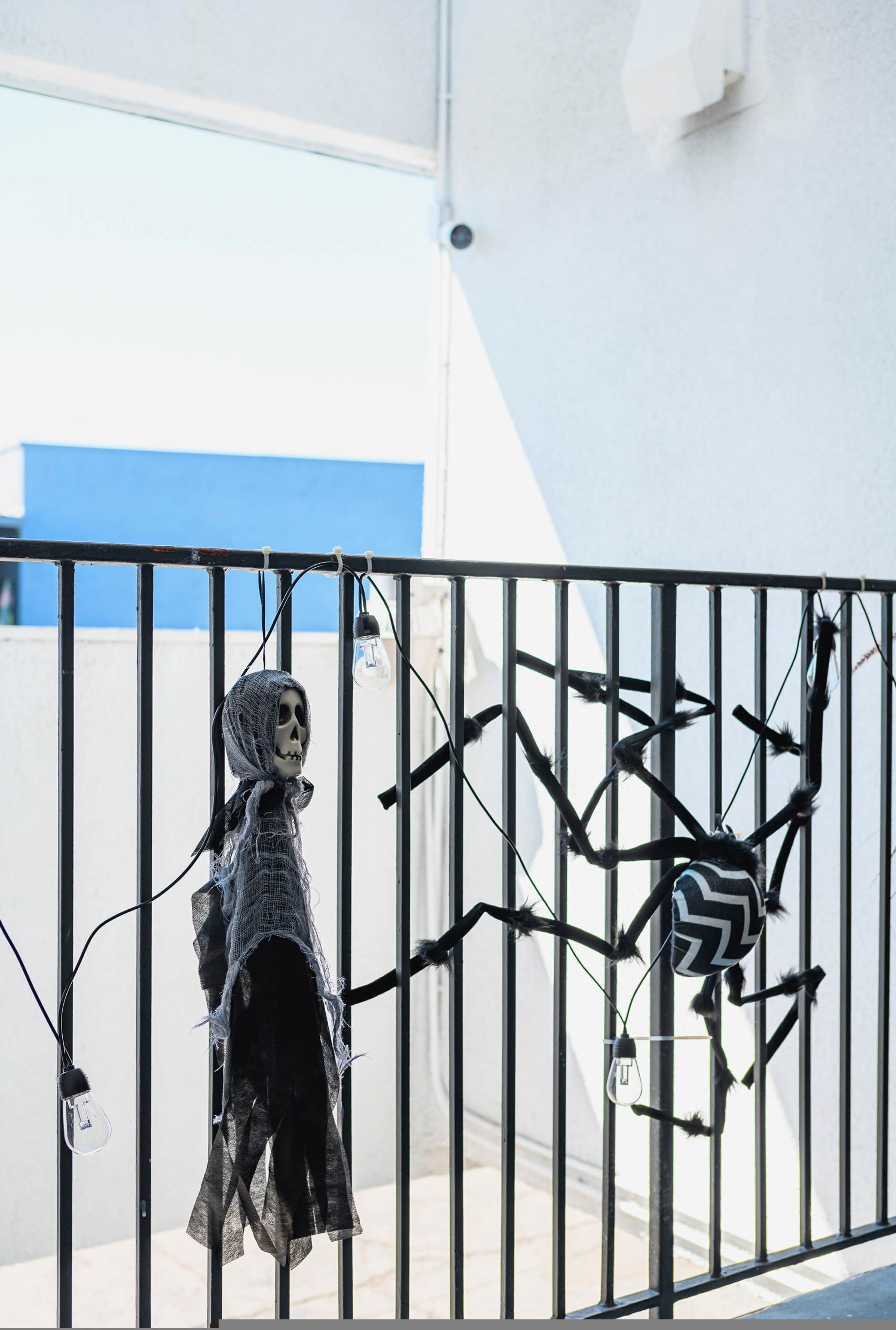 Et skelet og en edderkoppe skulptur på gelænderet til en balkon.