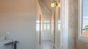 Ein schmaler, modern gestalteter Flur mit einer Couch, einem kleinen Tisch und einem Fenster mit Blick nach draußen.