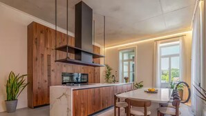 Eine moderne Küche mit Holzschränken, einer zentralen Kochinsel und einem Essbereich mit rundem Tisch und Stühlen.