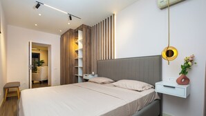 A modern bedroom with a large bed, bedside tables, a wall-mounted shelf, and a hanging light fixture.