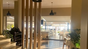 A spacious indoor area with wooden flooring, a staircase, and several hanging pendant lights. - Rumar Hotel (Durres)