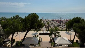 A beach view with umbrellas and beach chairs, a sandy area, and a clear sky. - Rumar Hotel (Durres)