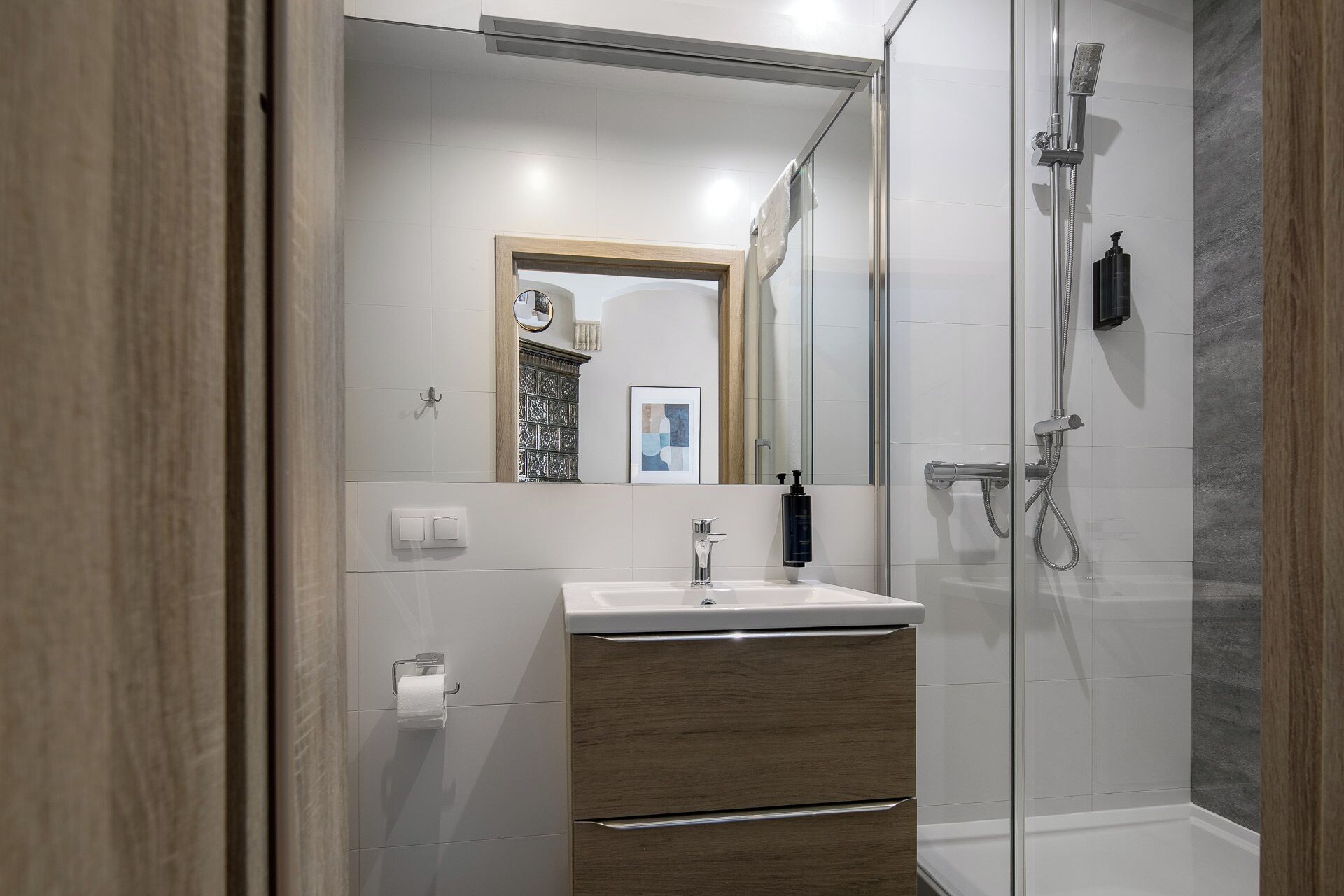 A modern bathroom with a glass shower enclosure, a sink with a wooden vanity, and a mirror above the vanity.