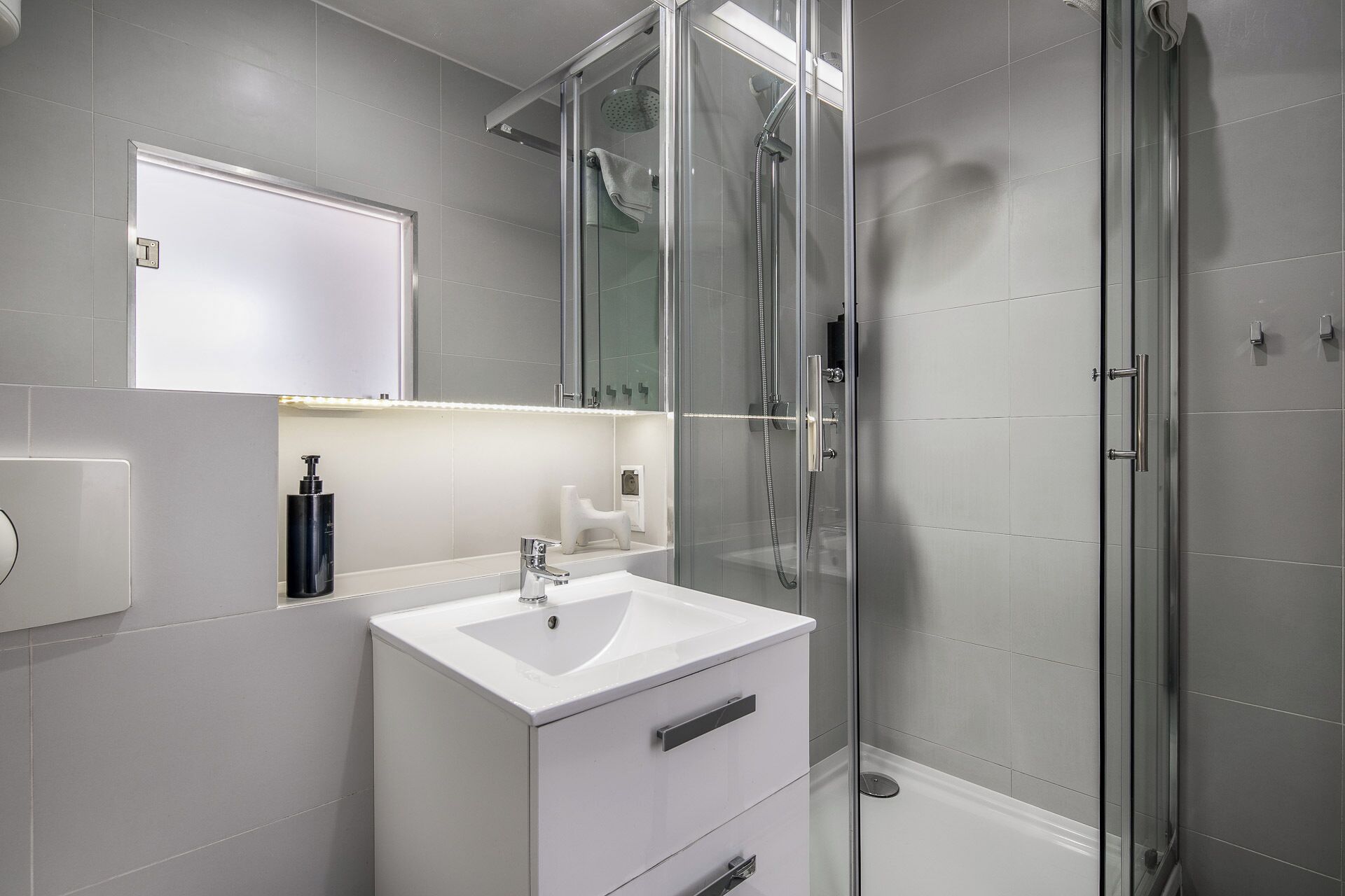 A modern bathroom with a glass-enclosed shower, a white sink, and a mirror above the vanity.