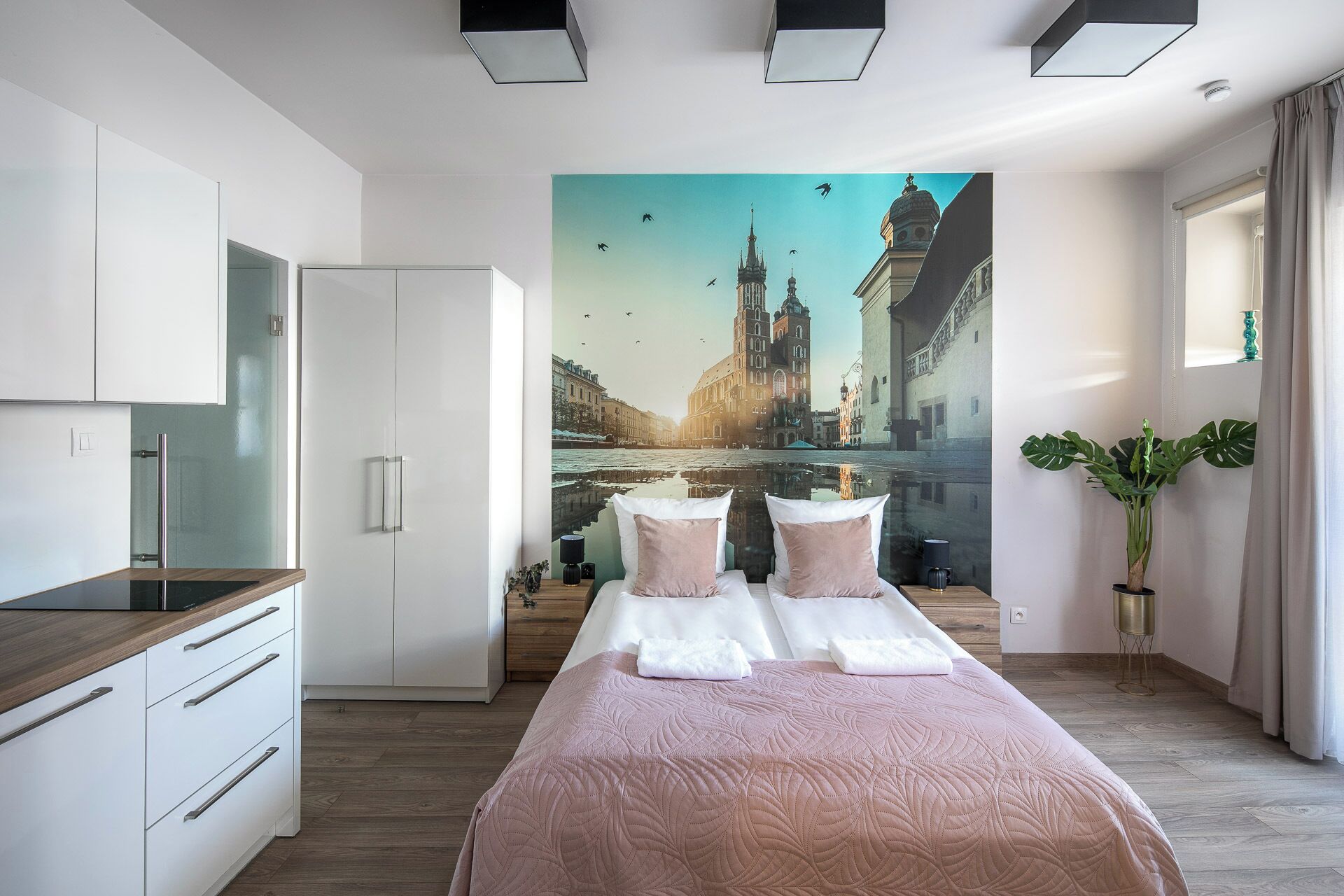 A modern bedroom with a large bed, a desk, and a wall mural of a cityscape.
