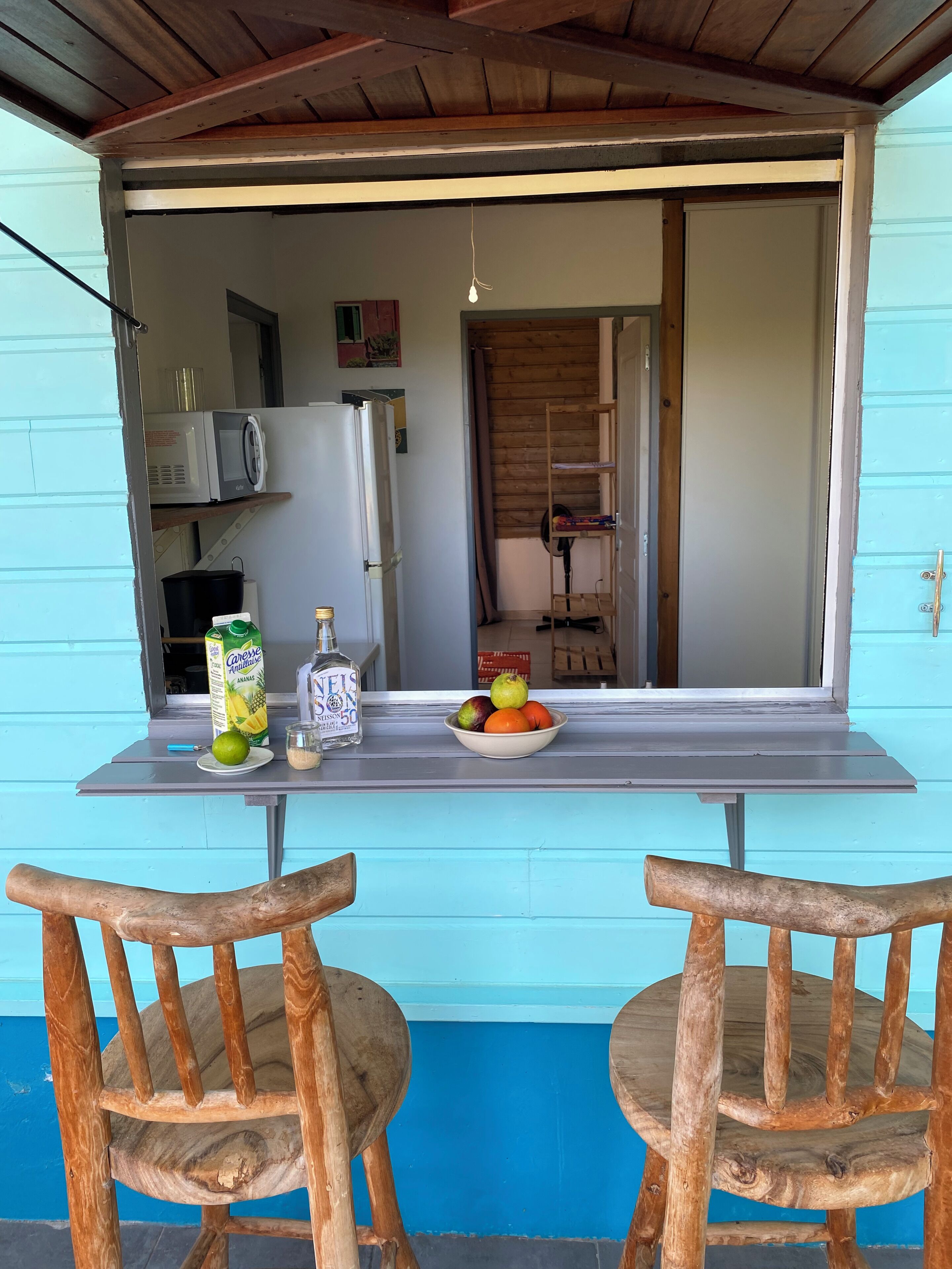 A kitchen with a table set for two, a microwave, a refrigerator, and a wooden chair.