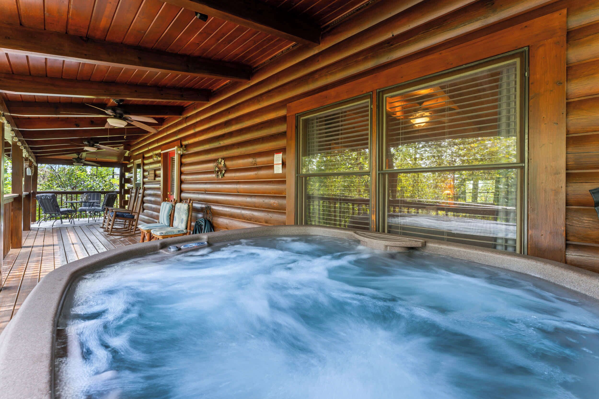 Une cabane en bois dotée d’un bain à remous, d’une terrasse en bois et de grandes fenêtres.