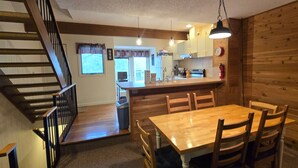 Un intérieur en bois comprenant une table à manger, des chaises, un coin cuisine et un escalier.