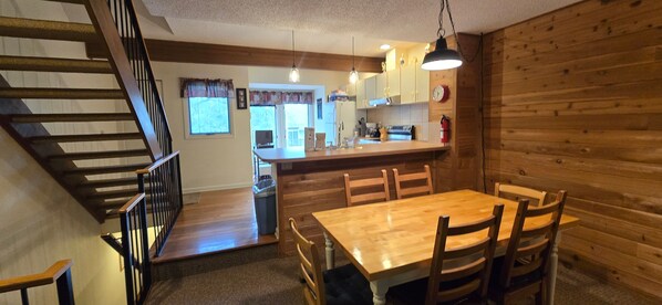 Un intérieur en bois comprenant une table à manger, des chaises, un coin cuisine et un escalier.