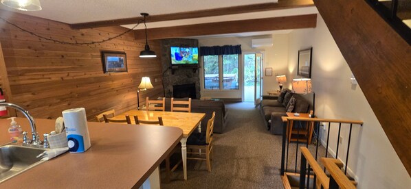 Un intérieur de chalet chaleureux comprenant un coin repas, un salon et une cheminée.