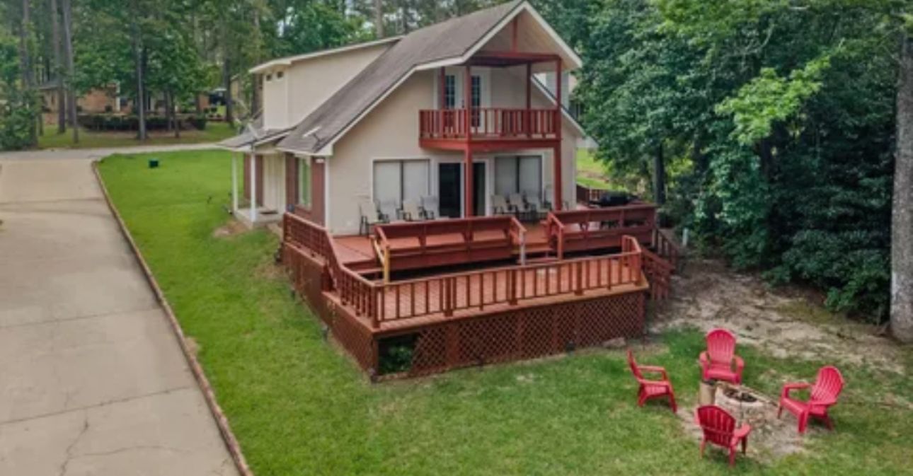 A two-story house with a balcony, a deck, and outdoor seating.