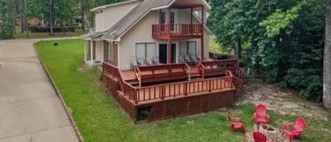 A two-story house with a balcony, a deck, and outdoor seating.