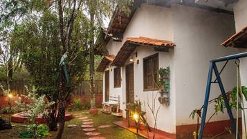 Una casa rústica con techo de tejas, un pequeño porche y un jardín con piedras para caminar.