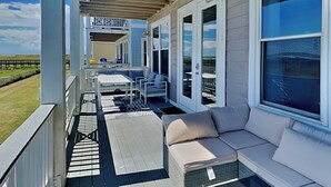 Un espace extérieur abrité, aménagé avec des sièges, une petite table et offrant une vue sur la plage.