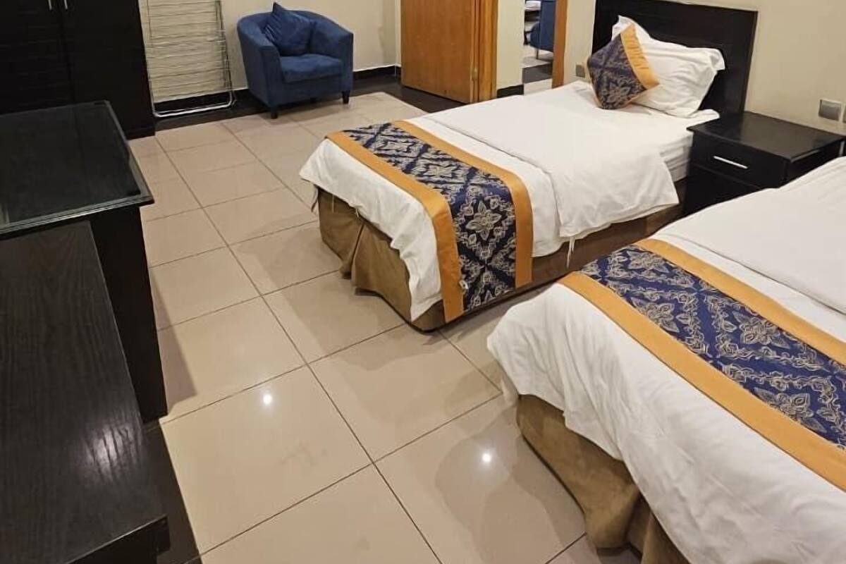 Une chambre d’hôtel avec deux lits, un bureau, une armoire et un plafond doté d’un éclairage encastré.