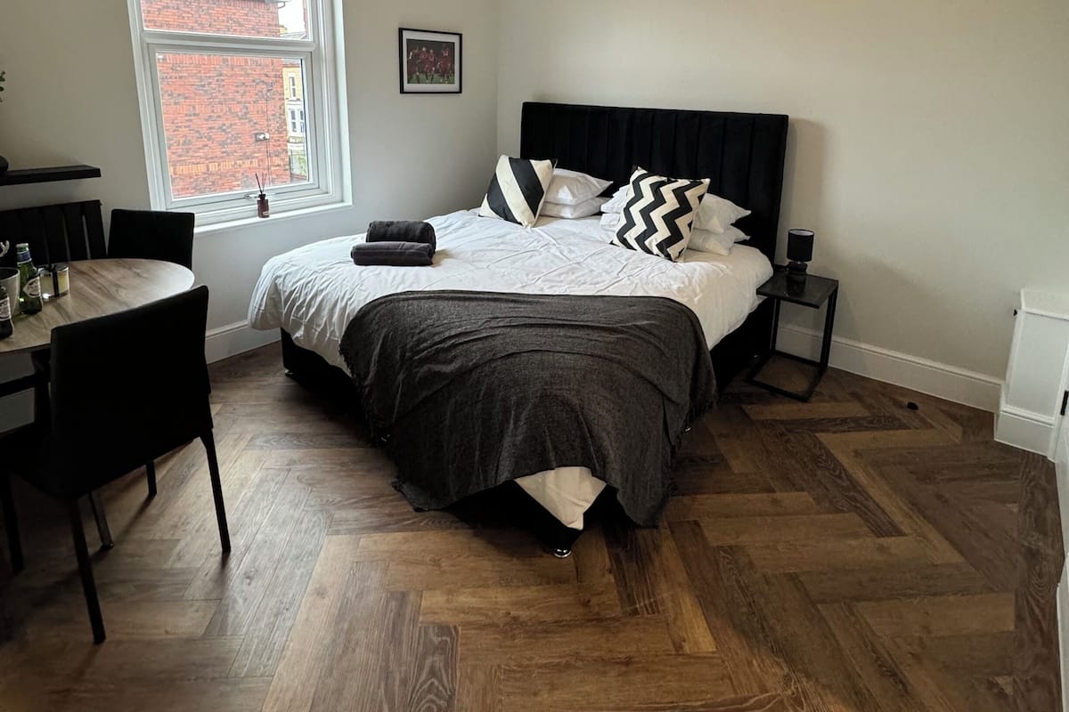 A bedroom with a bed, bedside table, and a window.