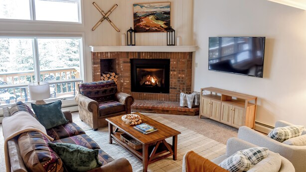 Een gezellige woonkamer met een open haard, comfortabele zithoek en een grote televisie.
