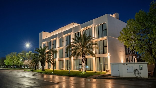 A modern building with a flat roof, large windows, and a well-lit entrance. - RM Campana Hotel (Campana)