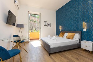 Une chambre moderne avec un lit, des tables de chevet, un téléviseur et une table en verre avec des chaises.