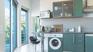 A modern kitchen with a built-in washing machine, a microwave, and a coffee machine. - Pitanga by Atlantic Holiday (Camara de Lobos)